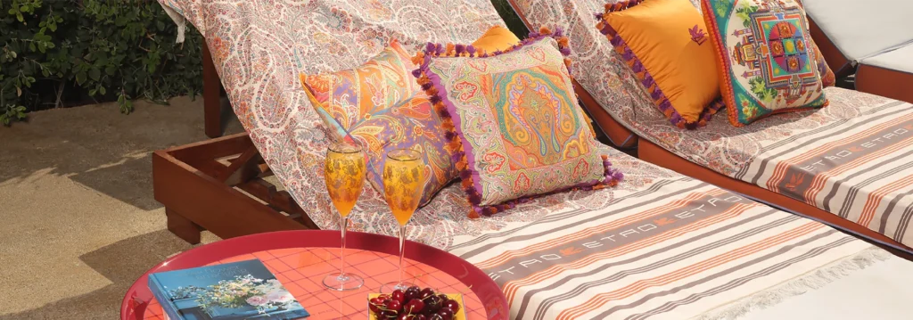 Outdoor loungers styled with ETRO HOME designer cushions and throws by the pool — luxury summer home decor