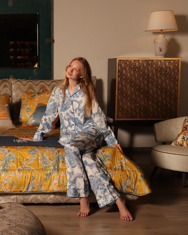 Woman in luxury cotton pyjamas on a designer upholstered bed with premium bedding, decorative cushions, luxury bedroom furniture and elegant summer home décor